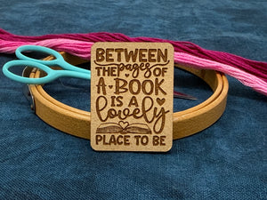 photo of a needle minder featuring text saying "Between the pages of a book is a lovely place to be."