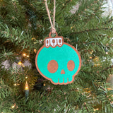 Green hand-painted Creepy Christmas skull bulb ornament hanging on a Christmas tree.