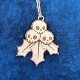 Unpainted Creepy Christmas Skull Holly Berry laser cut wood ornament laying on a blue background.
