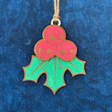 Hand-painted Creepy Christmas Skull Holly Berry laser cut wood ornament laying on a blue background.