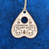 Unpainted Summoning the Holiday Spirit Oija Planchette Ornament on a blue background.